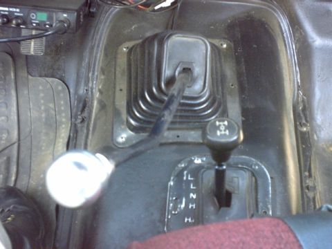 1976 Chevrolet C/K Pickup - The interior of a vehicle features a CB radio and two gear shifters, one with a chrome knob.