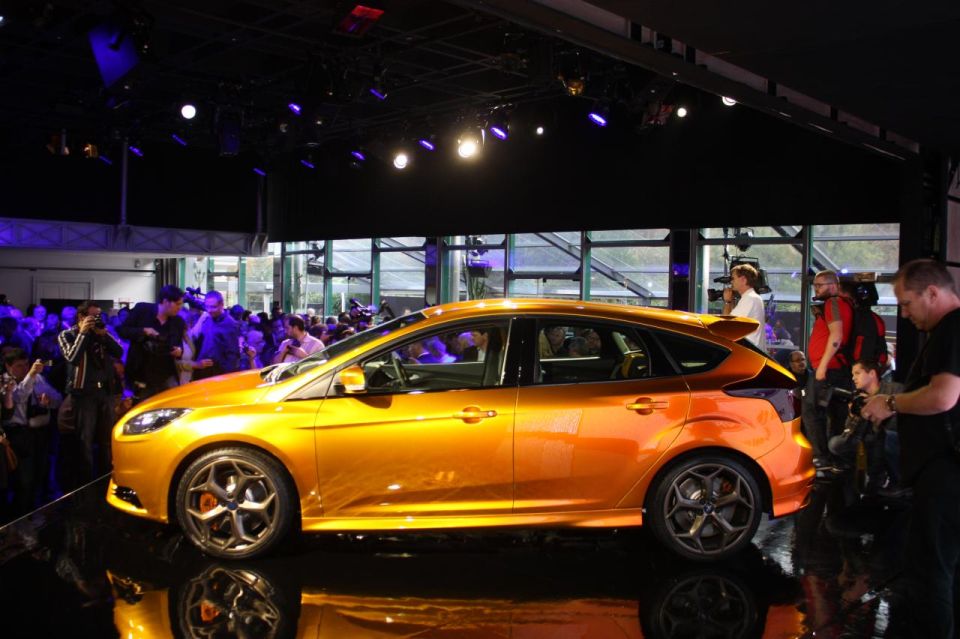 Orange hatchback car with a rear spoiler, seen from the side