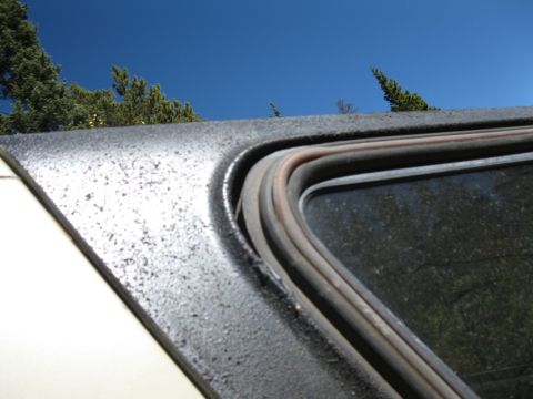 1978 Ford Bronco - The worn window seal on a vehicle is visible against a clear blue sky.