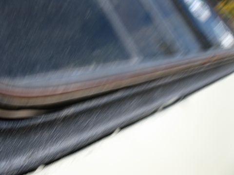 1978 Ford Bronco - A close-up view of a car's window seal shows a dark rubber gasket with a visible layer of rust or discoloration beneath it.