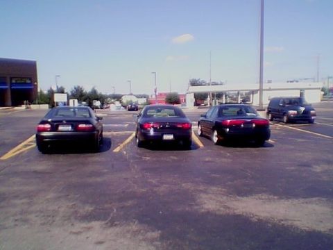 1999 Ford Taurus - Multiple vehicles are parked in a lot under a clear sky.