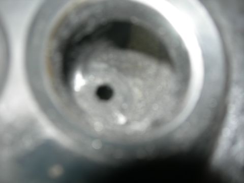 1984 Ford Bronco - A close-up view of a dirty engine component, possibly a cylinder head, with a central hole. The Supermotors.net logo is visible in the lowe…
