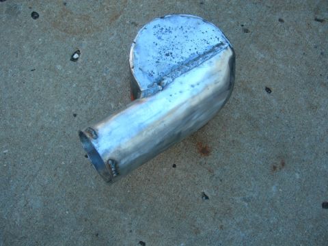 1984 Ford Bronco - A custom-fabricated exhaust pipe, likely for a vehicle modification, rests on a concrete surface.