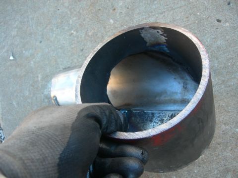 1984 Ford Bronco - Close-up of a metal exhaust pipe section with internal welds, held by a gloved hand.