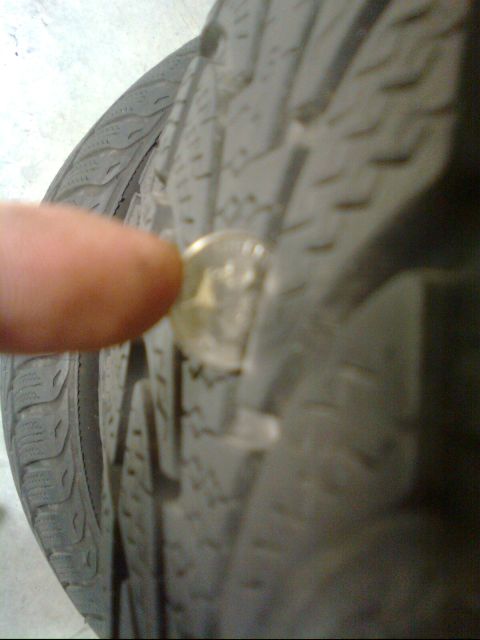 1989 Ford Probe - A coin is used to check the tread depth on a tire. The registry claims this is a 1989 Ford Probe, but the image only shows a tire part.