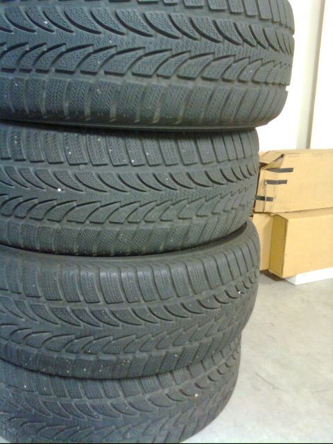 1989 Ford Probe - Four tires are stacked on top of each other indoors.