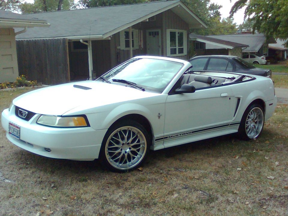 White convertible Mustang with side stripe and aftermarket wheels