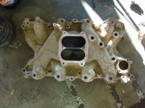 1989 Ford Bronco - An aluminum intake manifold, likely for a V8 engine, is shown from above on a workshop floor.