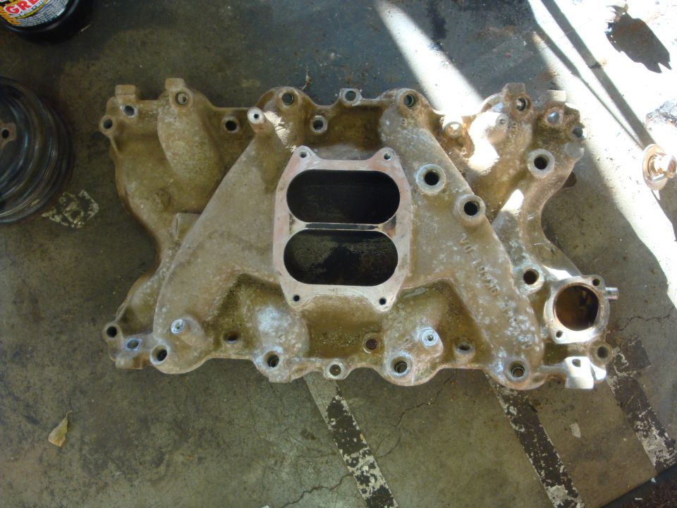 Aluminum intake manifold with two large openings, resting on a concrete floor