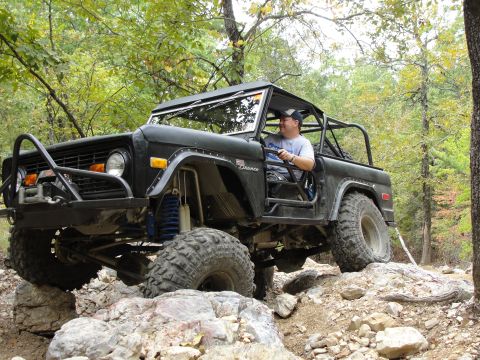 1967 Ford Mustang - A driver maneuvers a modified black Ford Bronco through a challenging off-road course.