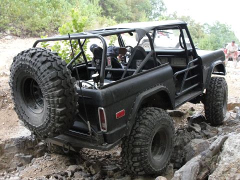1967 Ford Mustang - Modified black Ford Bronco navigates a rocky trail, its off-road capabilities and custom roll cage.
