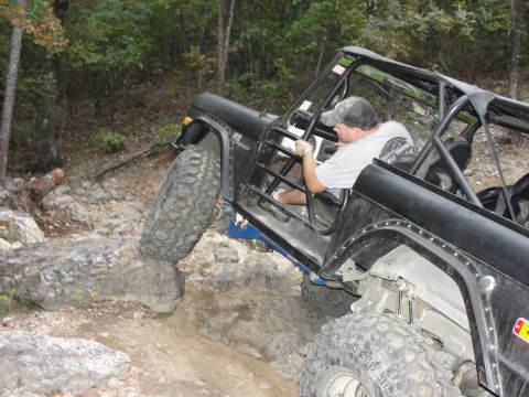 1967 Ford Mustang - A driver maneuvers a modified off-road vehicle over challenging rocks on a trail.