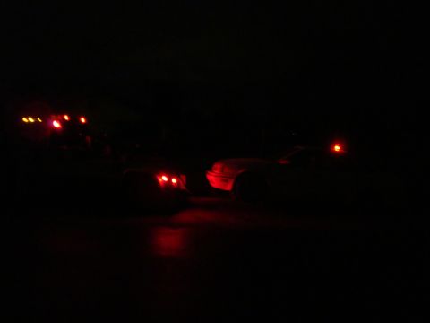 1990 Ford Taurus - Two vehicles are visible at night, their red lights reflecting on the ground.