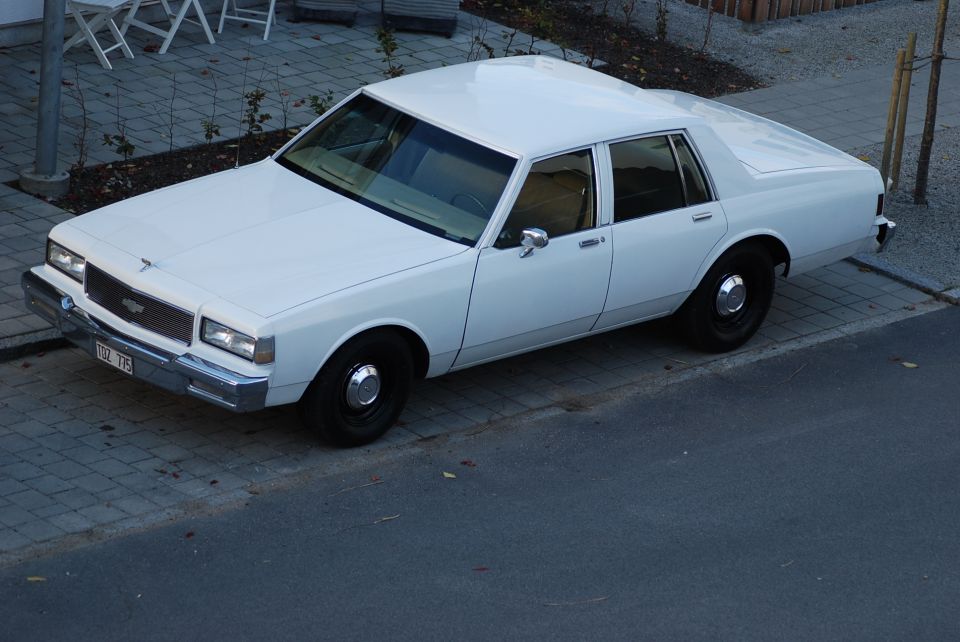 White sedan, 3q front view. License plate reads 102 775
