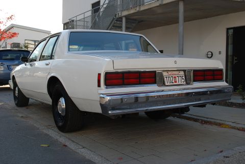 1998 Ford Crown Victoria - This sedan features a distinctive chrome bumper and large, rectangular taillights, indicative of an 80s model.