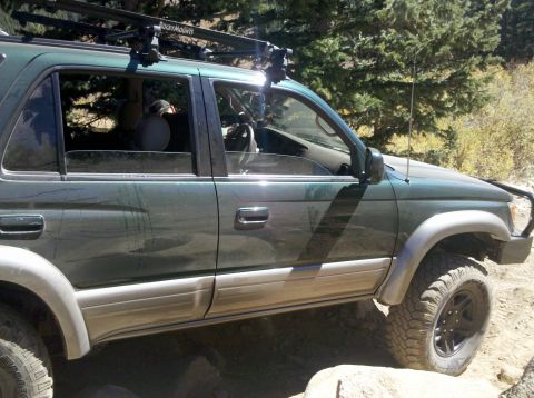 1996 Ford Bronco - Dark green SUV with a roof rack on a dirt road, possibly off-roading.
