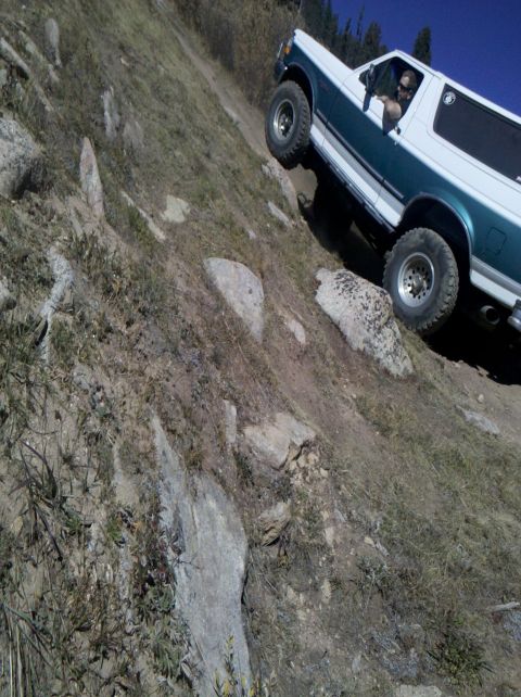1996 Ford Bronco - This two-tone Ford Bronco is navigating a challenging off-road trail on a steep incline.