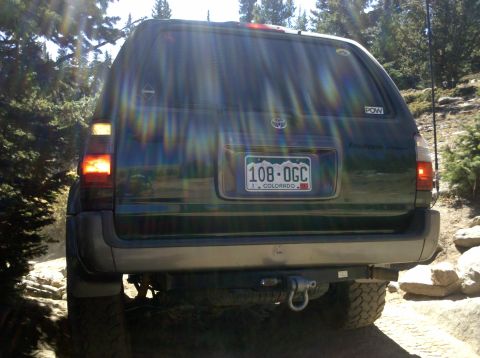 1996 Ford Bronco - Rear view of a dark green SUV on a rocky, off-road trail.