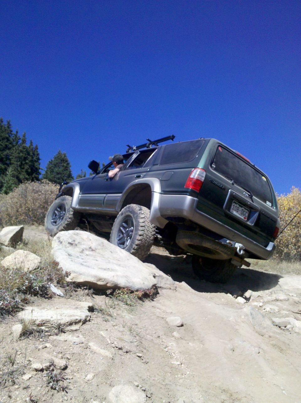 Dark green SUV with off-road tires climbing a rocky incline
