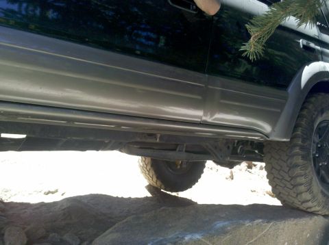 1996 Ford Bronco - The lower body panels and undercarriage of an SUV are visible as it navigates over large rocks.