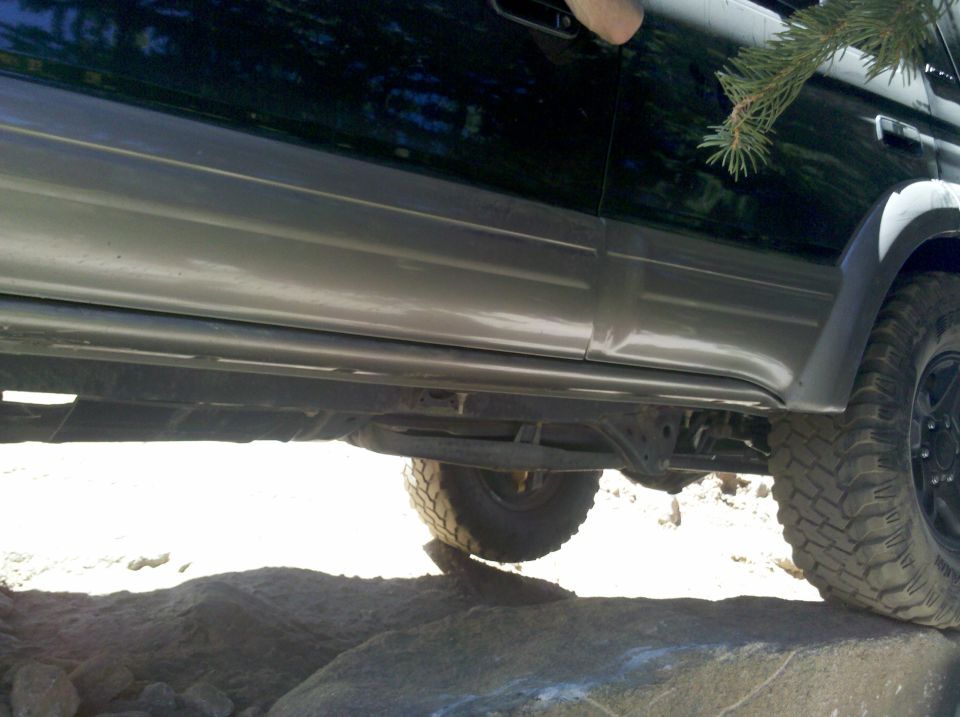 Side of an SUV with two-tone paint and running boards, driving over rocks