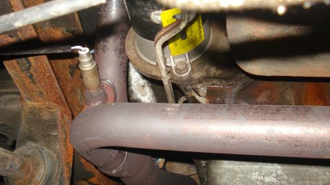 1988 Ford Bronco - Close-up of an exhaust system component, likely an oxygen sensor and catalytic converter.