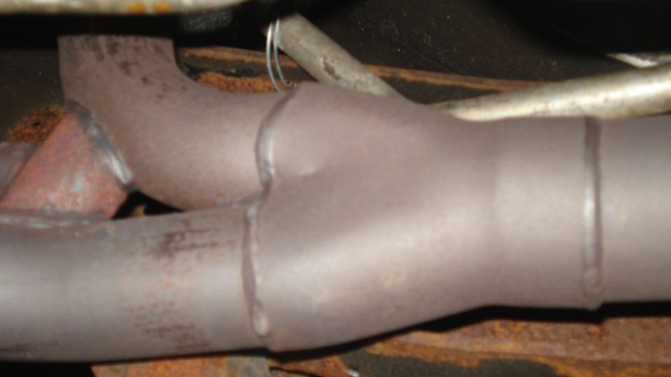 Exhaust pipe Y-junction with visible welds and rust