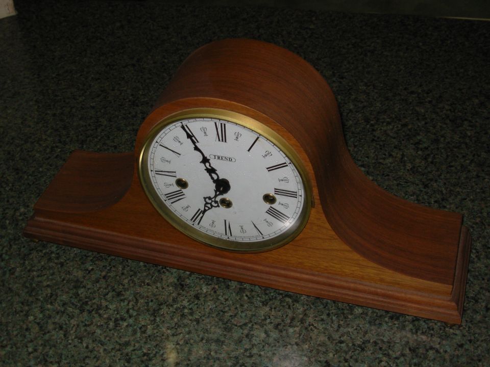 TREND wooden tambour mantel clock with white Roman numeral dial on a green countertop
