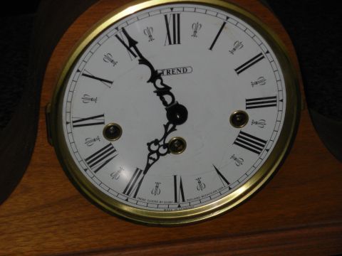 2004 Land Rover Land Rover - Close-up of a clock face with Roman numerals and the TREND logo.