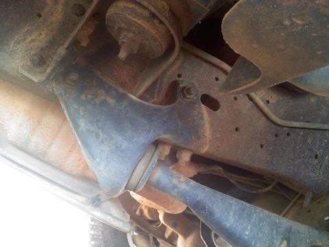 1990 Ford Bronco - Close-up of the undercarriage shows the vehicle's suspension system with signs of wear and tear.