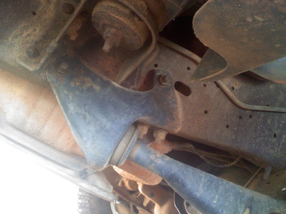 Underside view of rusty vehicle suspension with visible bolts and metal brackets