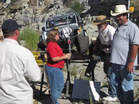 1989 Ford Bronco - A group of people observe a heavily modified Jeep Wrangler at an outdoor event.