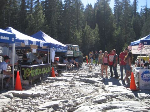 1989 Ford Bronco - An outdoor event with tents set up on a rocky terrain, people and an off-road vehicle.