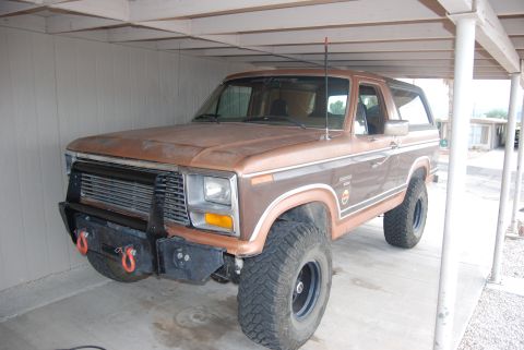 1982 Ford Bronco - This modified Ford Bronco, likely from the early 1980s, features a custom front bumper and off-road tires.