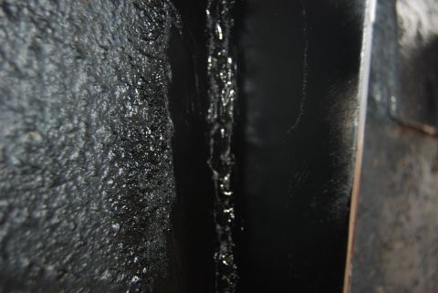 1982 Ford Bronco - The underside of a vehicle shows a textured coating with some areas of dripping material.