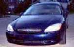 2000 Ford Taurus - The front grille and headlights of a dark blue sedan are visible.