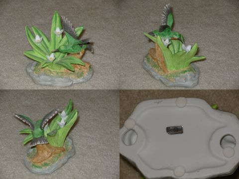 2004 Land Rover Land Rover - A ceramic figurine depicts two hummingbirds near green foliage and white flowers, with a manufacturer's label visible on the base.