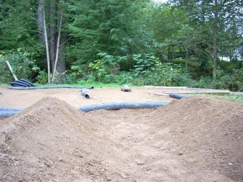 1994 Ford Escort - A remote control car is on a dirt track surrounded by pipes and mounds of dirt.