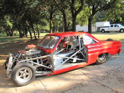 1963 Ford Fairlane - A red 1963 Ford Fairlane drag car is parked outdoors, an exposed engine, roll cage, and racing slicks.