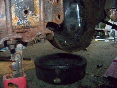 1989 Ford Bronco - A drain pan is positioned under a rusty vehicle suspension component during maintenance.