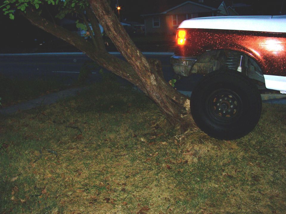 1992 Ford Bronco front corner with orange turn signal on, parked on grass near a tree