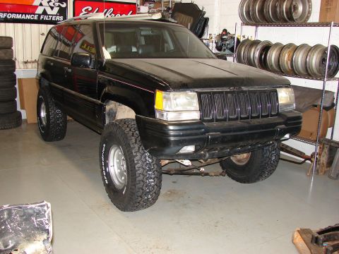 1996 Jeep Grand Cherokee - This Jeep Grand Cherokee is modified with larger tires and suspension lift, shown in a workshop setting.