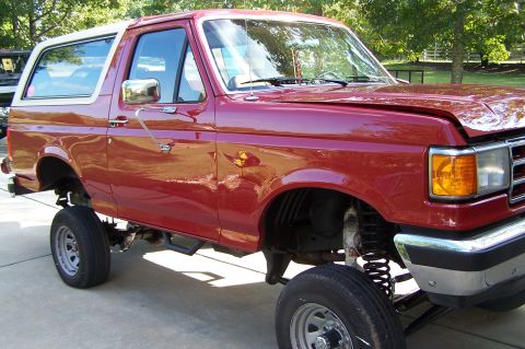 1990 Ford Bronco - This lifted Ford Bronco features a two-tone paint scheme with a red body and white removable top.