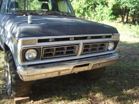 1986 Ford Bronco - The front grille of a weathered Ford truck sits outdoors with a can of soda on its hood.