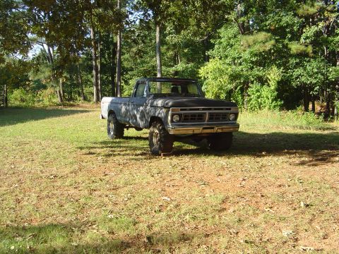 1986 Ford Bronco - This lifted pickup truck, likely from the mid-1970s, is parked in a grassy, wooded area.