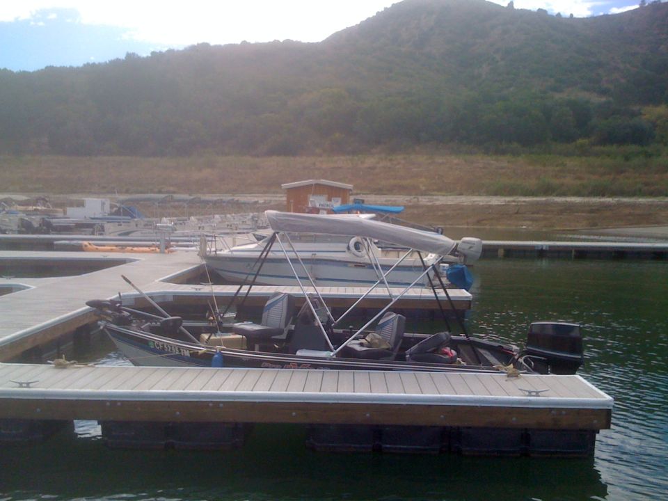 Fishing boat with a canopy and fishing rods on a dock, other boats nearby