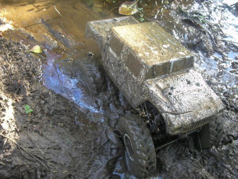 1994 Ford Escort - RC rock crawler navigating a muddy stream, showing off its off-road capabilities.