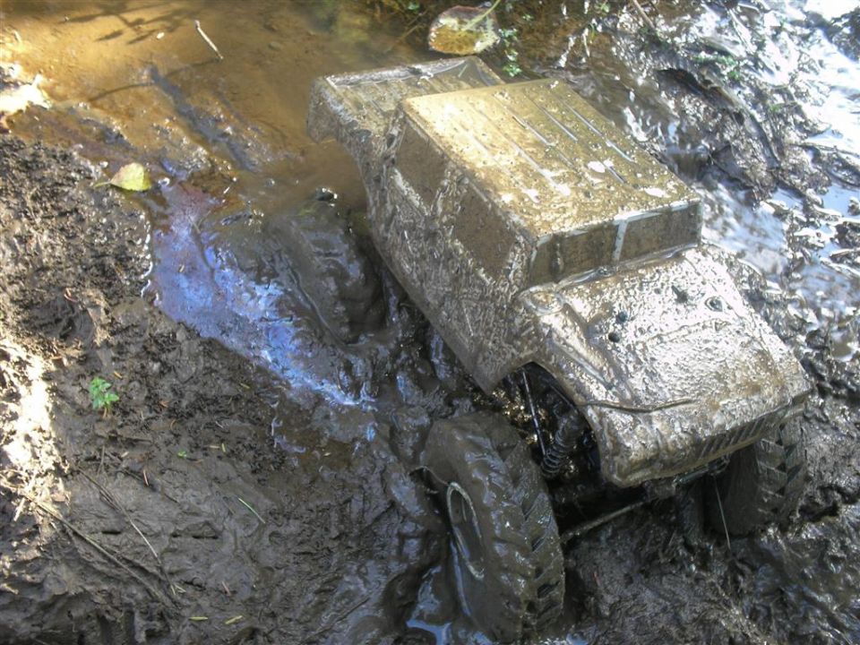 Mud-covered remote control rock crawler stuck in muddy water