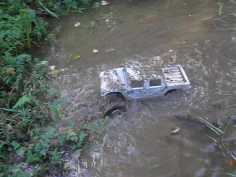 1994 Ford Escort - A toy truck is stuck in the mud, surrounded by water and vegetation.