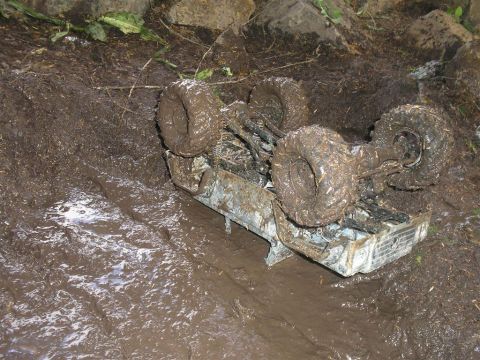 1994 Ford Escort - This vehicle is completely stuck in thick mud, overturned on its side.